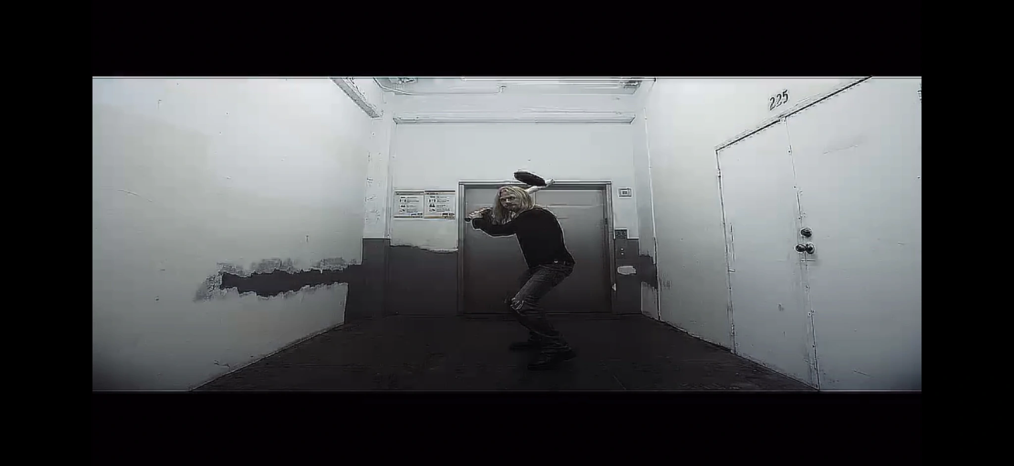 A figure moving in a white hallway, with intentional top and bottom letterboxing