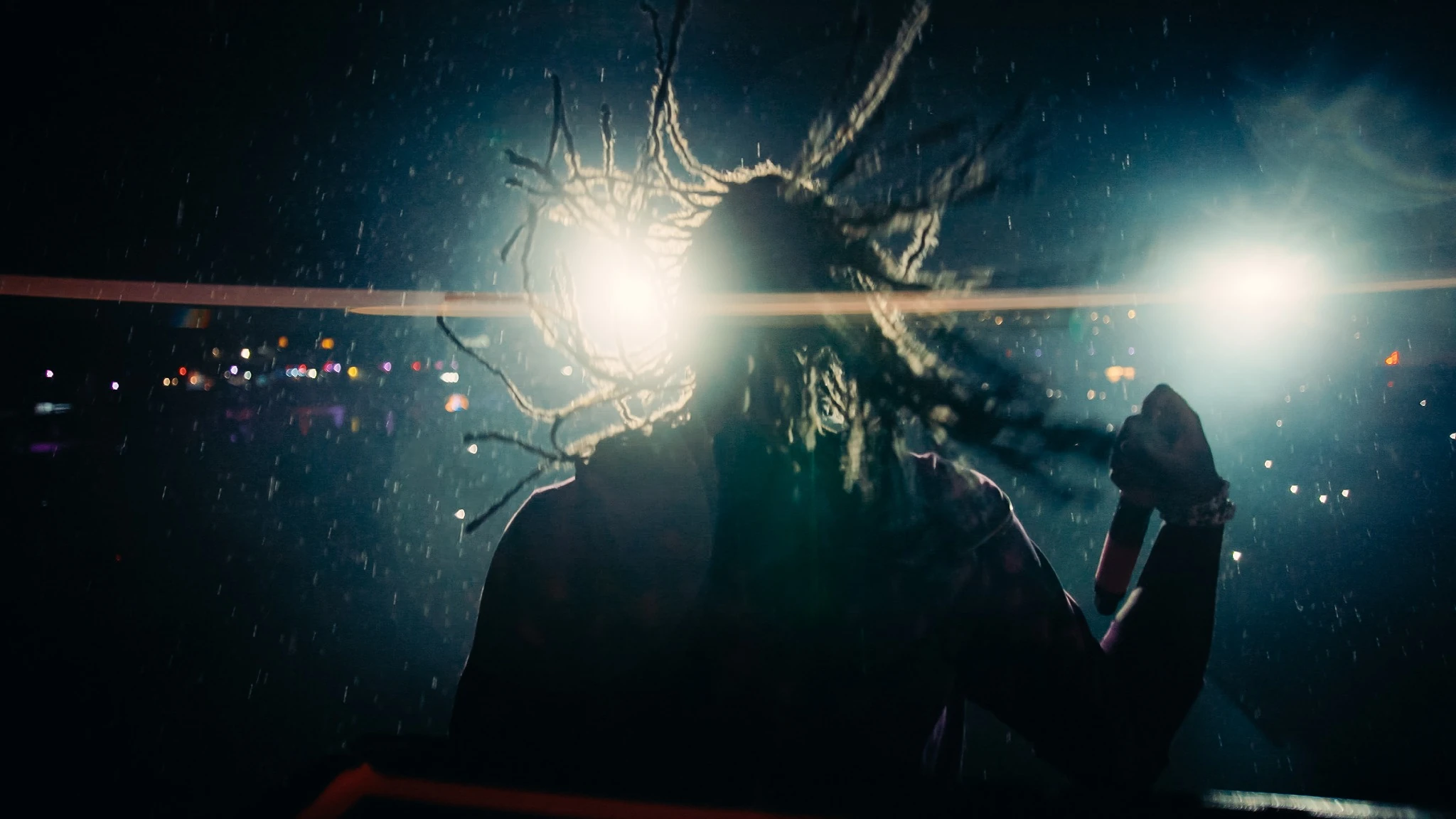 A performer in motion, backlit by the crowd lights in the rain