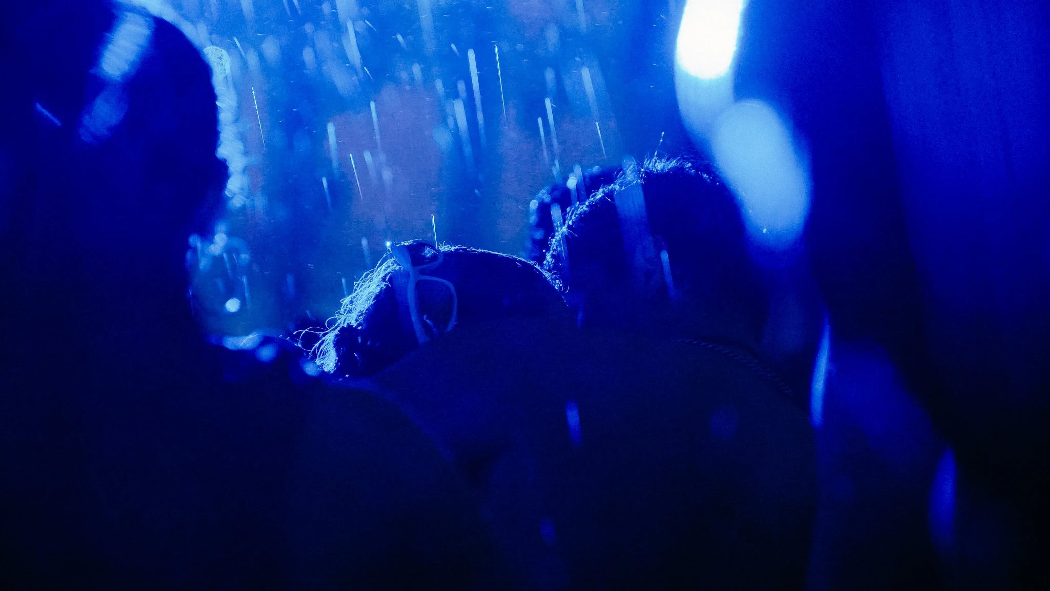 A close moment between the performers under deep blue light