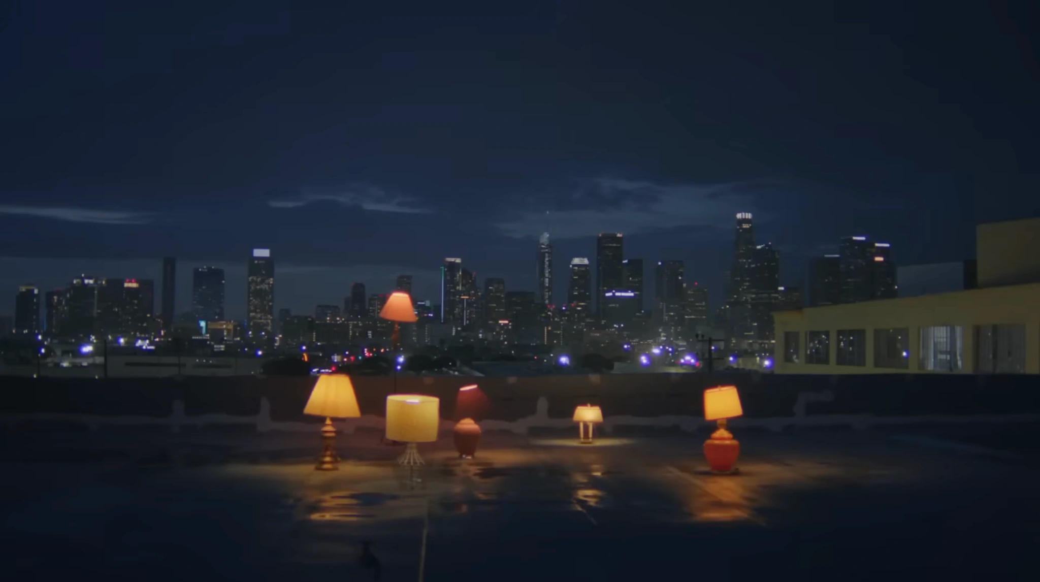 Glowing lamps on a rooftop at dusk with the Los Angeles skyline behind them