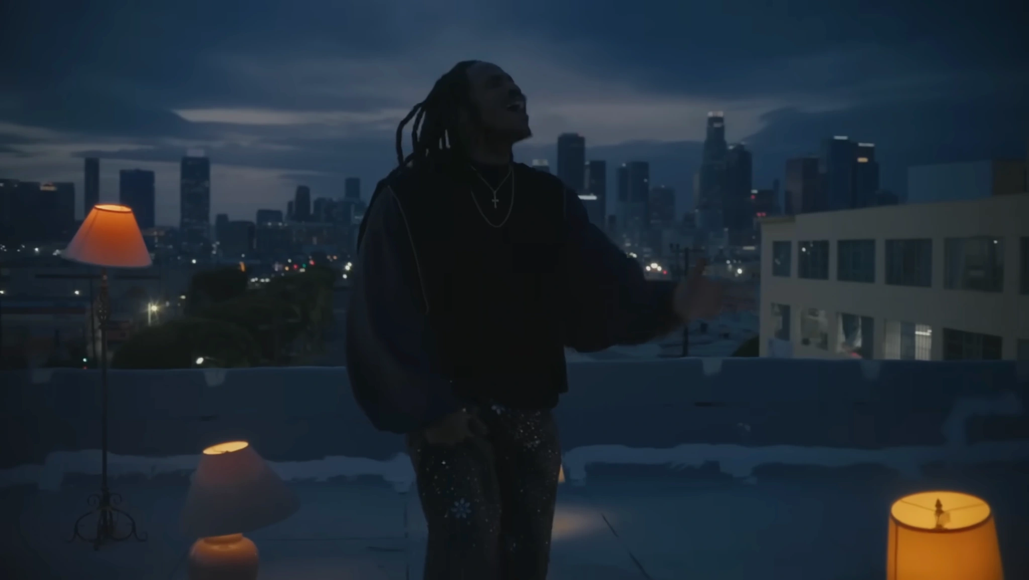 SiR performing among warm lamps on a rooftop at dusk