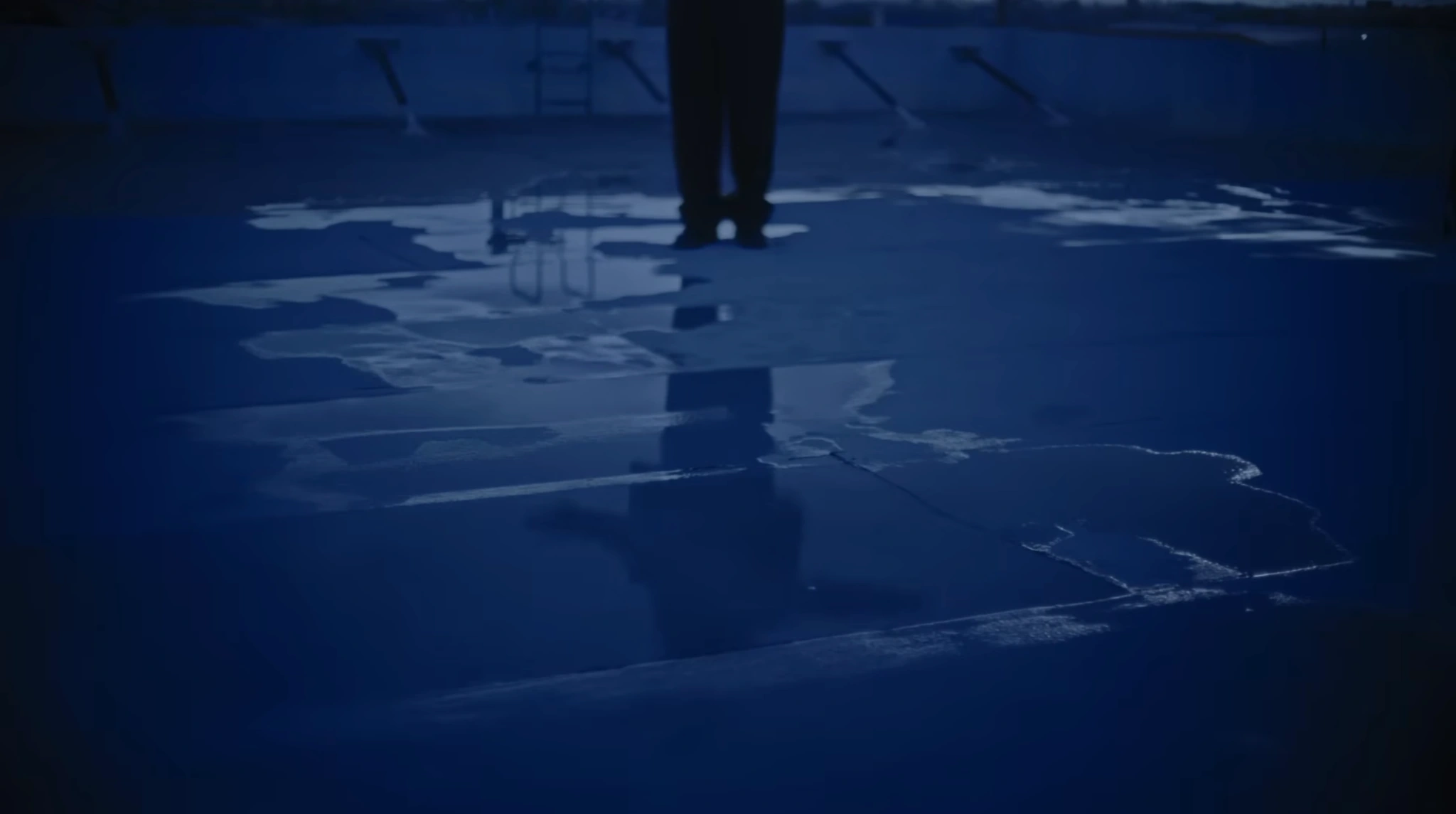 A blue-lit reflection of a figure on a wet rooftop